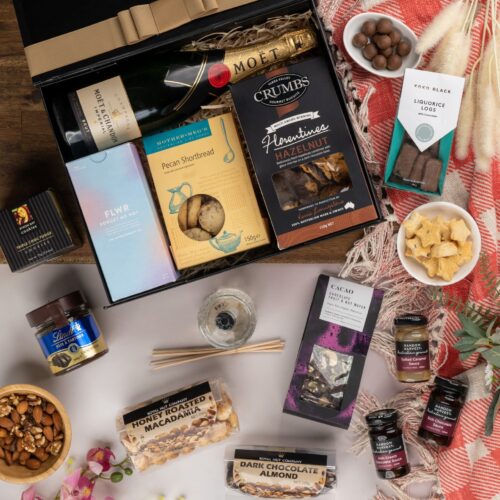 In this captivating flat-lay image, an array of carefully selected props encircles a gift hamper, creating a visual narrative. Discover a captivating collection of items within the gift hamper, carefully chosen to create a truly unforgettable experience. This gift hamper contains: Desert Sauce; Biscuits; Chocolate; Nuts; Sparkling Wine; Diffuser