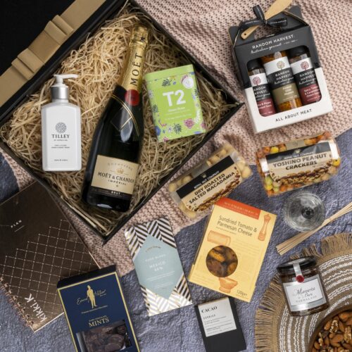 In this visually striking flat-lay composition, an assortment of props is elegantly arranged around a gift hamper, evoking a sense of luxury and sophistication. Discover a captivating collection of items within the gift hamper, each one thoughtfully chosen to create a truly remarkable experience, taking the recipient on a journey of delight and surprise. This gift hamper contains: Hand And Body Wash; Tea (Green); Sparkling Wine; Jam; Mustards and Dressings; Planners; Crackers; Nuts; Chocolate; Diffuser