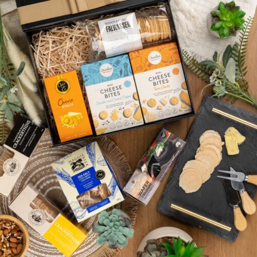 A visual symphony of colors unfolds in this mesmerizing flat-lay composition, as an assortment of props surrounds a gift hamper. Open the gift hamper to reveal a delightful surprise waiting to be enjoyed, a perfect gift for any recipient. This gift hamper contains: Biscuits; Crackers