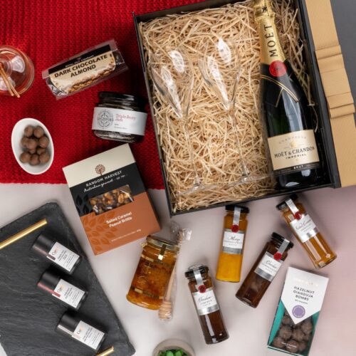 An artful arrangement of props weaves a story of anticipation and surprise in this captivating flat-lay photograph. The gift hamper holds an enchanting array of carefully selected surprises, each one contributing to a memorable and magical experience, filling the recipient's heart with wonder and creating a moment of pure enchantment. This gift hamper contains: Jam; Chocolate; Champagne Flutes ; Sparkling Wine; Honey
