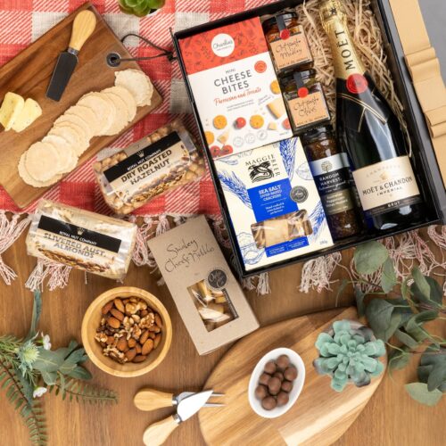 This enchanting flat-lay composition features a harmonious blend of props arranged artfully around a gift hamper. Inside the gift hamper, you'll discover a carefully curated collection of exquisite items, each one a testament to luxury and elegance. This gift hamper contains: Crackers; Nuts; Sparkling Wine; Mustards and Dressings; Antipasto; Biscuits