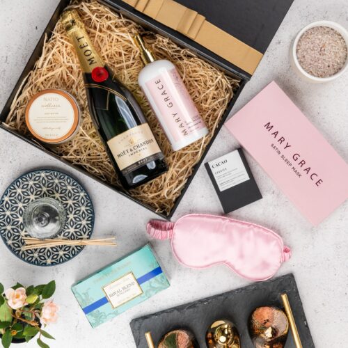 This captivating flat-lay composition entices the viewer with a carefully arranged assortment of props. Inside the gift hamper, you'll discover a carefully curated collection of exquisite items, each one a testament to luxury and elegance, ensuring a remarkable gift-giving experience that will be cherished and treasured, creating moments of pure happiness and pure indulgence. This gift hamper contains: Tea; Sleeping Mask; Diffuser ; Skincare; Sparkling Wine; Chocolate; Hand And Body Lotion